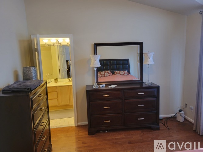 A bedroom with a large bed and a dresser with a mirror above it.