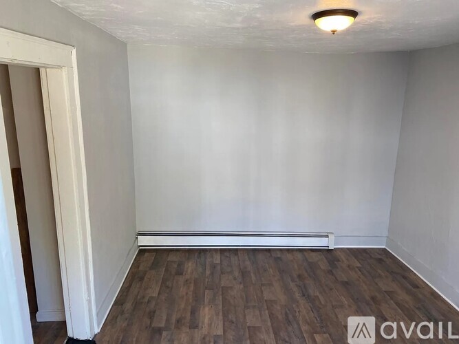 A room with wooden flooring and white walls.