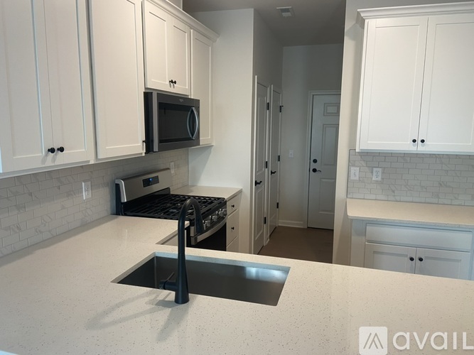 A kitchen with white cabinets and a black microwave above the stove.