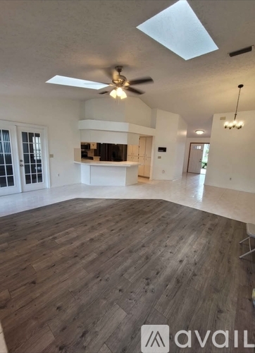 A spacious room with wooden flooring and a ceiling fan.