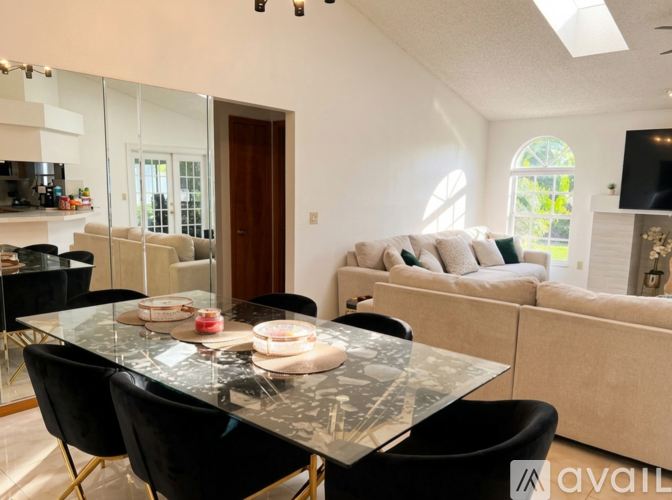 A modern dining room with a glass table and black chairs.