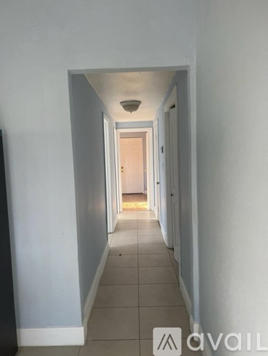 A long hallway with white walls and tile flooring.