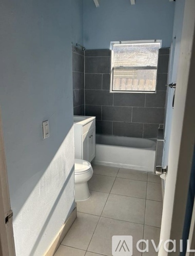 A bathroom with a toilet, a shower, and a window.