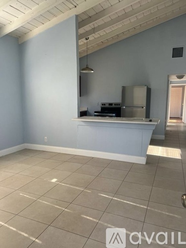 A room with a kitchenette and a large empty floor.