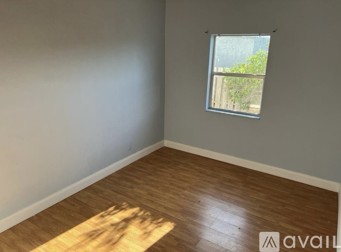 A room with wooden flooring and a window.