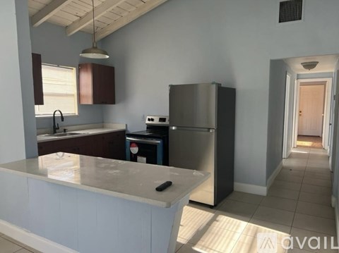 A kitchen with a refrigerator, sink, and countertop.