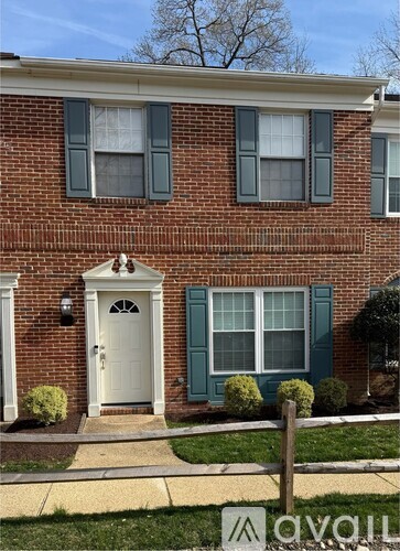 A red brick house with a white door and green shutters.