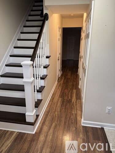 A hallway with a staircase and wooden floors.