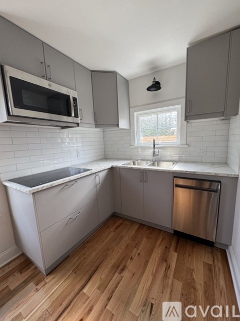 A kitchen with a white tiled backsplash and wooden floors.