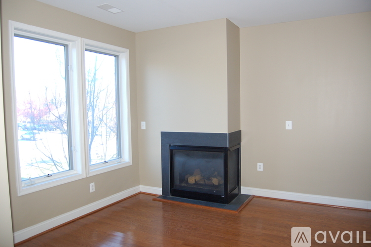 A living room with a fireplace and two windows.