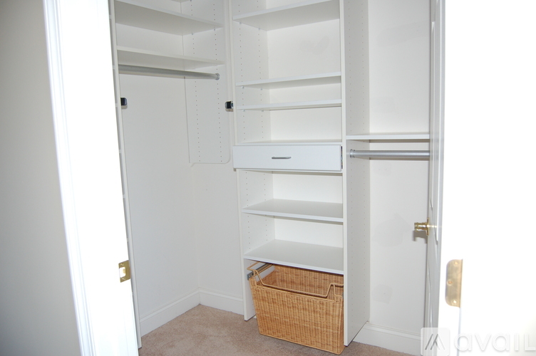 A white closet with a basket on the floor.