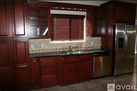 A kitchen with wooden cabinets and a stainless steel refrigerator.