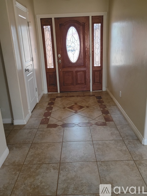 A hallway with a tiled floor and a wooden door with a glass window.