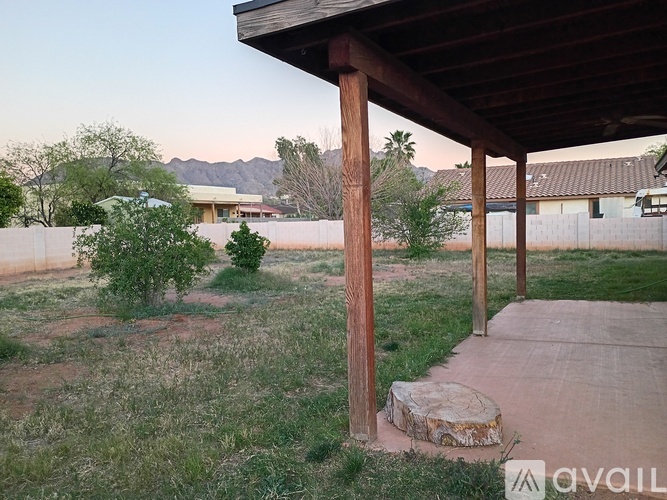 A wooden pergola is over a concrete walkway.
