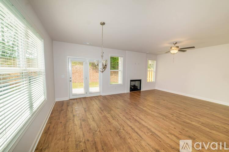 A spacious room with wooden floors and a chandelier hanging from the ceiling.