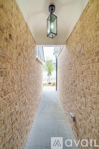 A narrow alleyway with a brick wall on either side and a hanging light fixture.