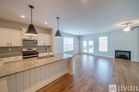 A kitchen with white cabinets and a wooden floor.