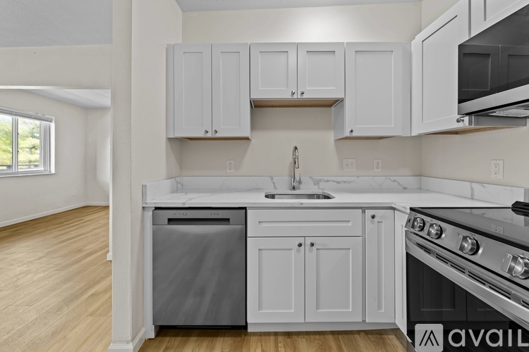 A kitchen with white cabinets and a marble countertop.