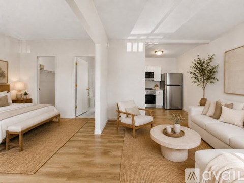 A spacious living room with a white sofa, wooden coffee table, and a large painting on the wall.