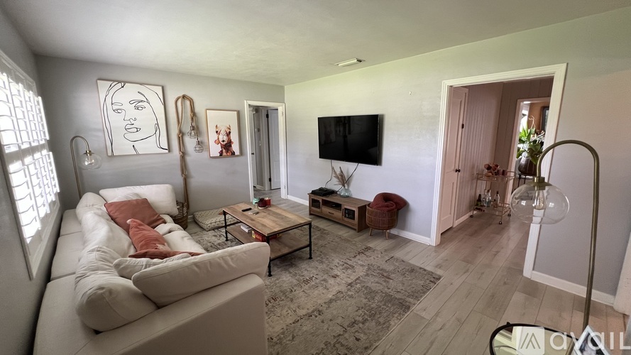 A living room with a white couch, a coffee table, and a television.