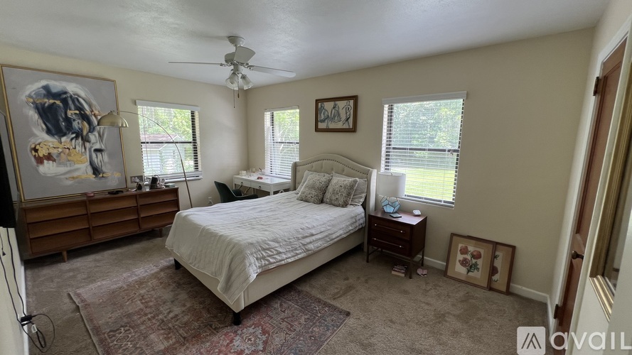 A bedroom with a bed, dresser, and ceiling fan.