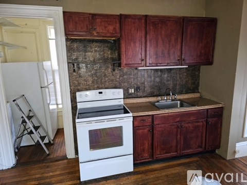 A kitchen with a white stove and wooden cabinets.
