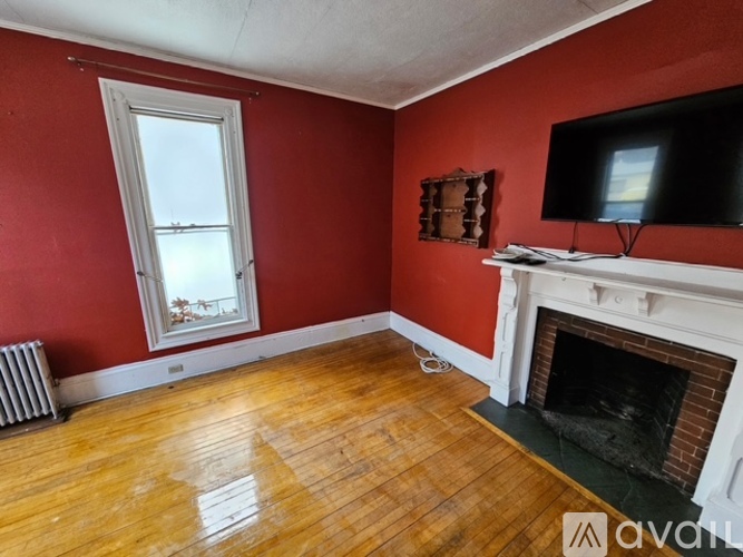 A room with red walls, a fireplace, and a television.