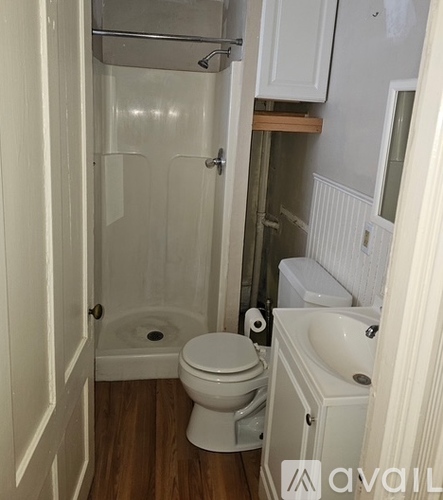 A white toilet is in a small bathroom with a walk-in shower.