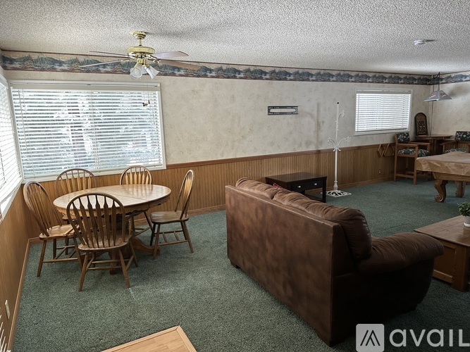 A living room with a brown couch, a round wooden table with chairs, and a ceiling fan.