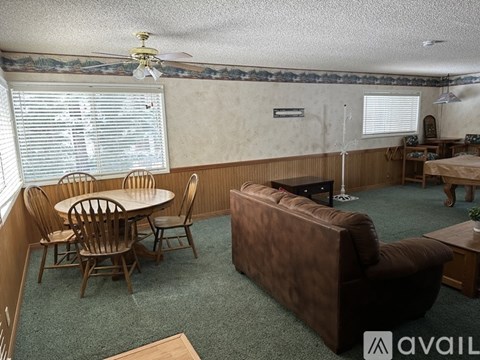 A living room with a brown couch, a round wooden table with chairs, and a ceiling fan.