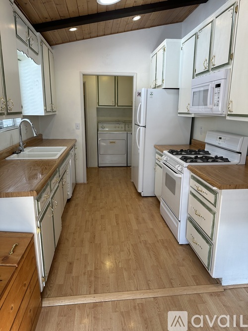 A kitchen with white appliances and wooden floors.