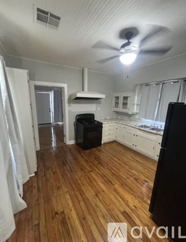 A kitchen with a black fridge and wooden floors.