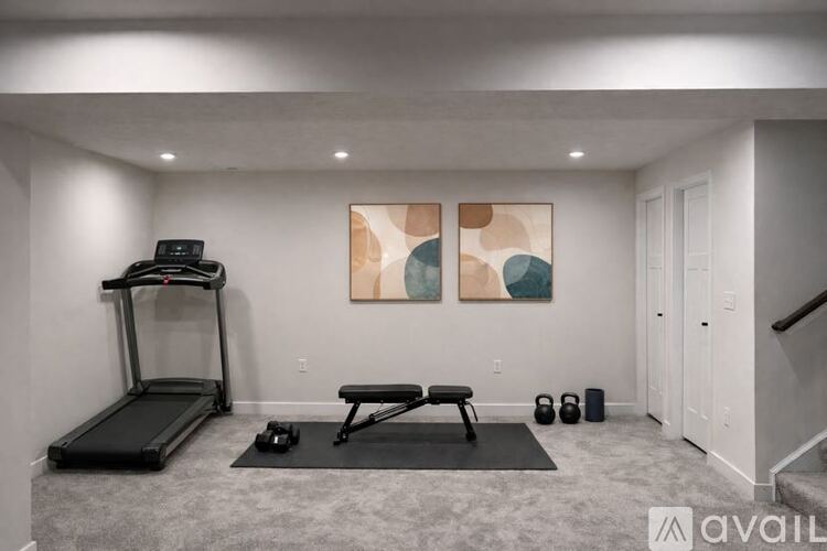 A home gym with a treadmill, bench, and weights.