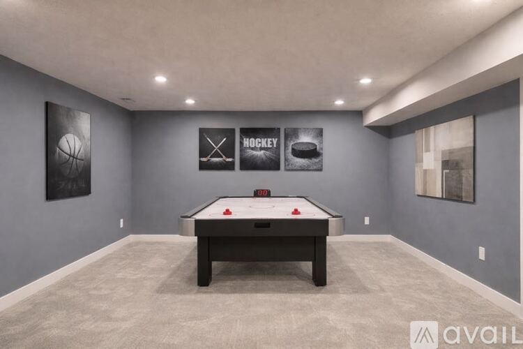 A pool table in a room with a grey wall and a picture of a basketball.