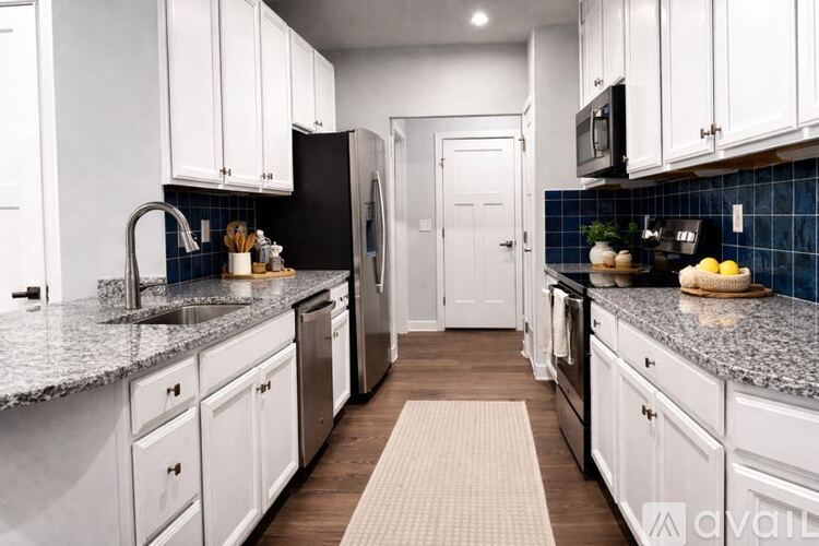 A kitchen with white cabinets and a black refrigerator.