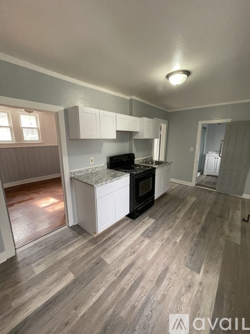 A kitchen with a black stove top oven and white cabinets.