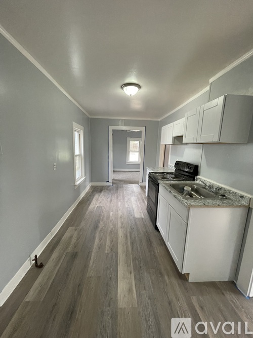 A kitchen with white cabinets and a wooden floor.