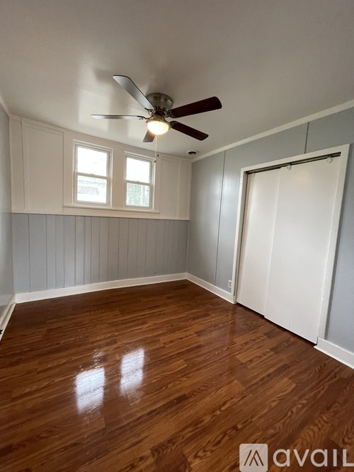 A room with a ceiling fan and wooden flooring.