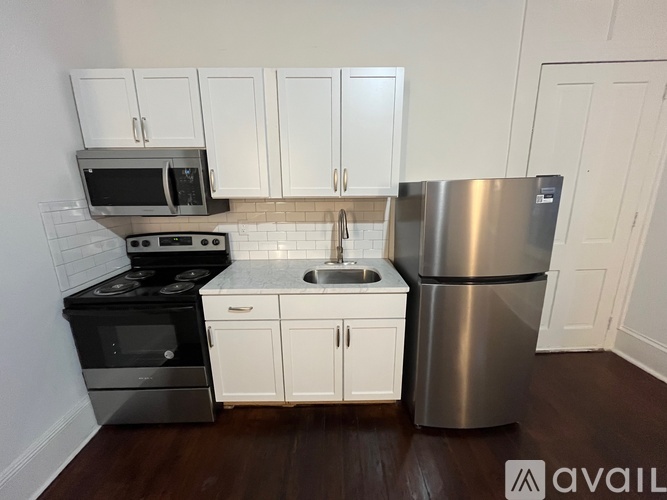 A kitchen with white cabinets and a stainless steel refrigerator.