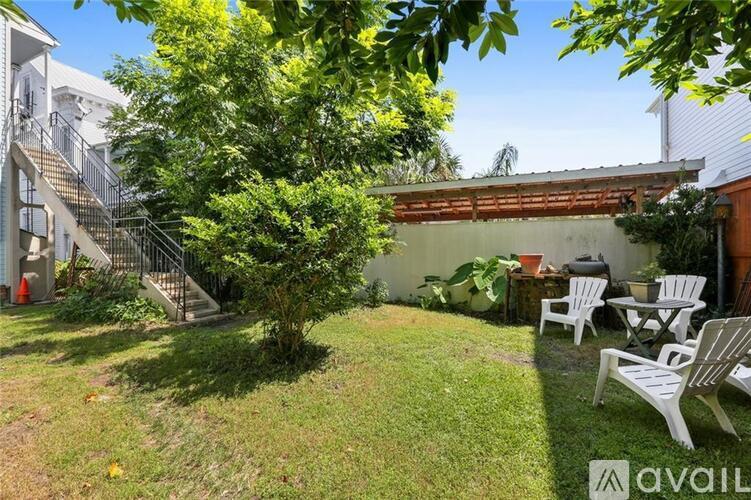 A backyard with a tree, chairs, and a building in the background.