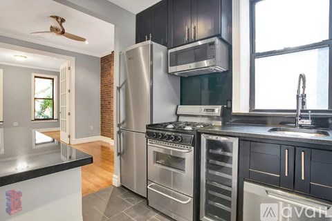 A modern kitchen with stainless steel appliances and black cabinets.