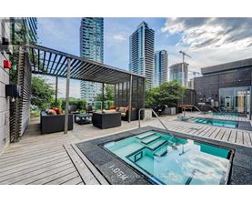 A modern outdoor seating area with a pool and a view of the city skyline.