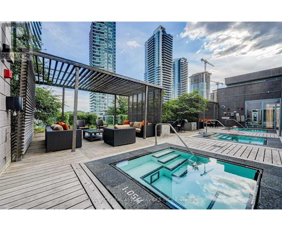 A modern outdoor seating area with a pool and a view of the city skyline.