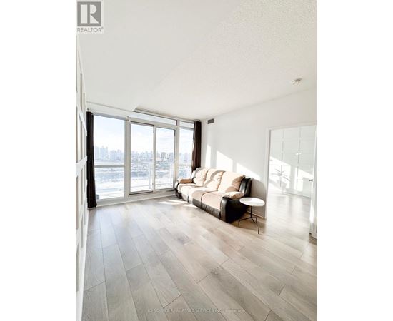 A living room with a couch and a large window overlooking a cityscape.