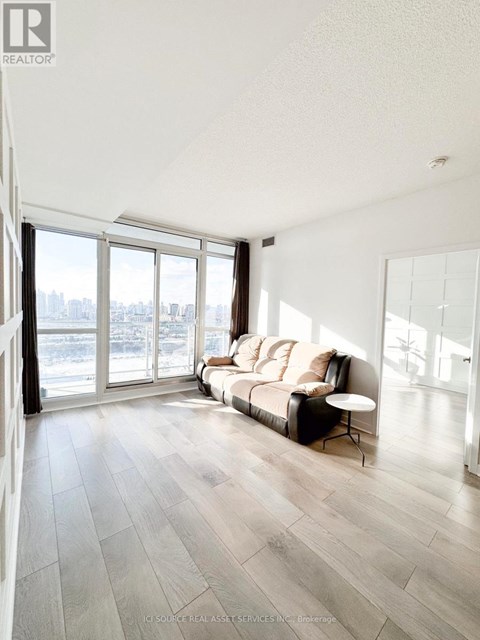 A living room with a couch and a large window overlooking a cityscape.