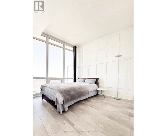 A bedroom with a large bed and a window overlooking the ocean.