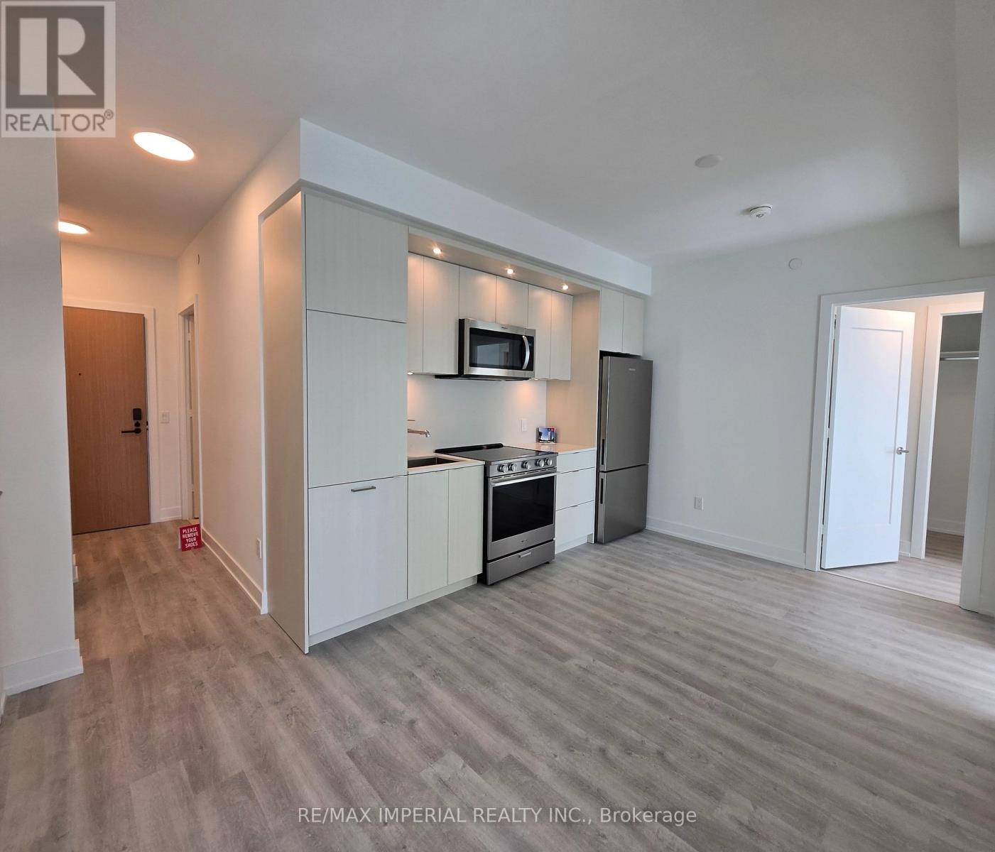 A modern kitchen with white cabinets and a wooden floor.