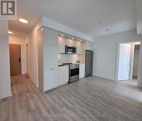 A modern kitchen with white cabinets and a wooden floor.