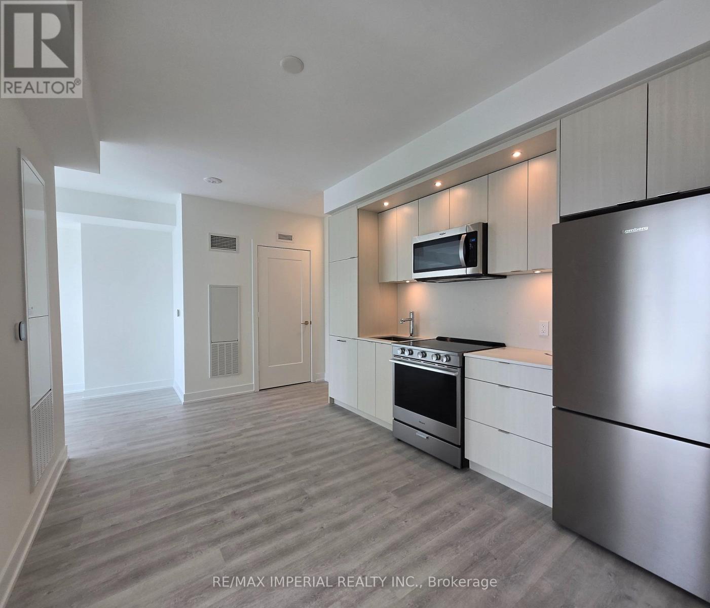 A kitchen with a refrigerator, oven, and microwave.
