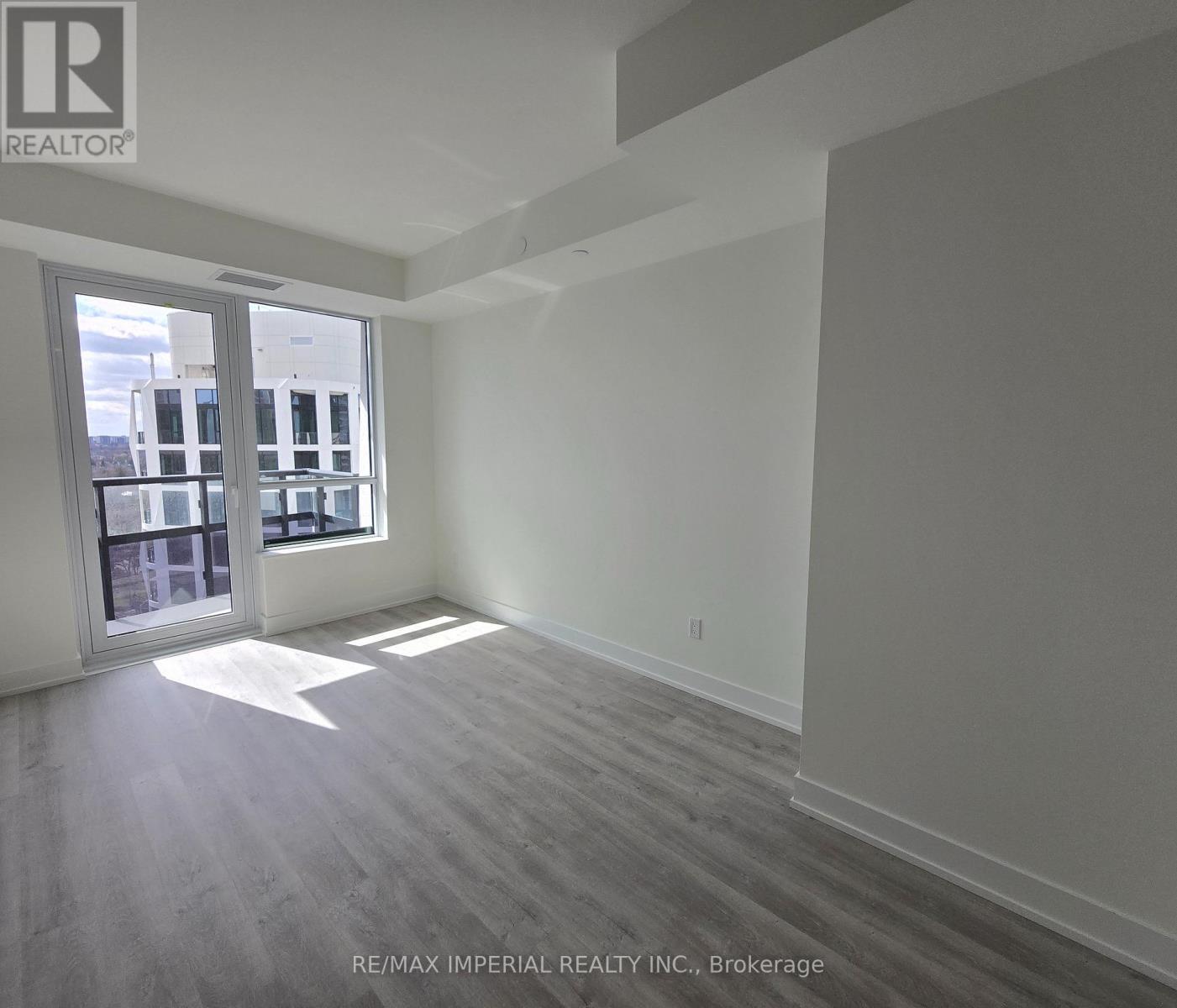 A spacious room with a large window and a view of a building outside.
